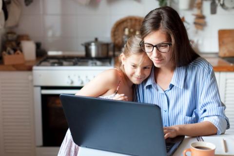 a mom and daughter looking at a laptop