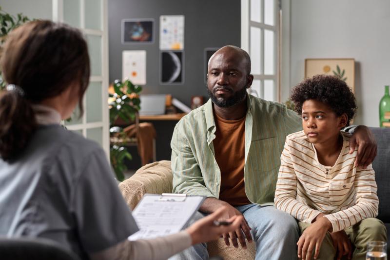 a black teen sitting down with his father across from a therapist