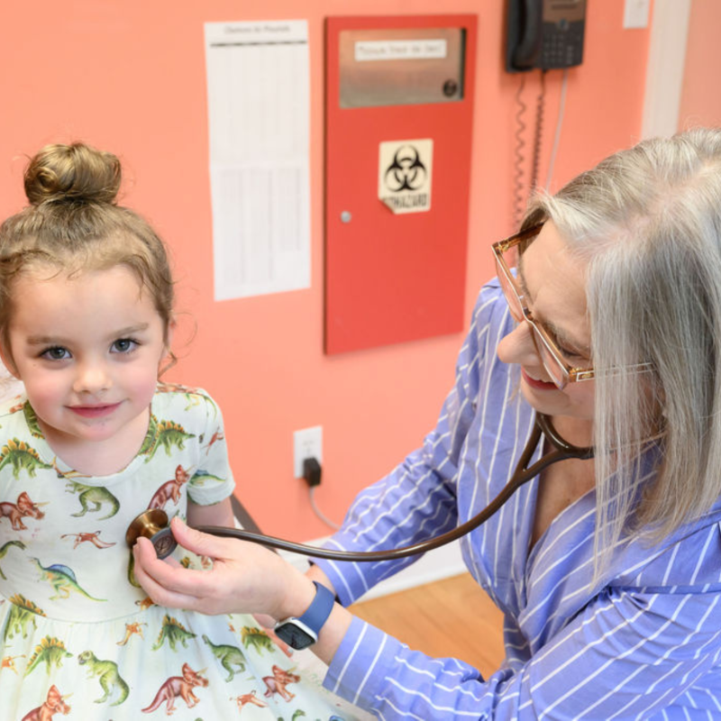 a female medical provider using a stethoscope to listen to a young girls heart