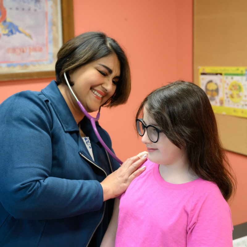 a female medical provider using a stethoscope with a young girl