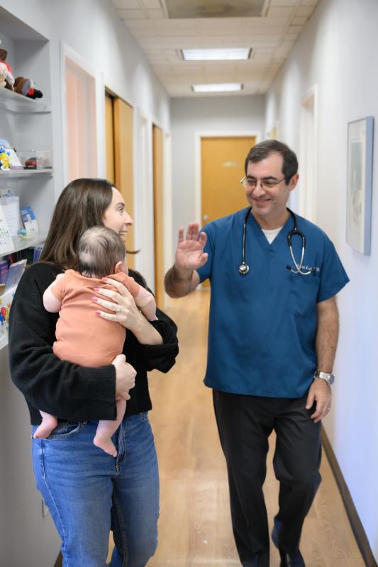 a doctor waving to a baby in a hallway