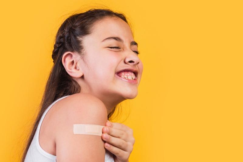 a girl wincing at a bandaid on her arm