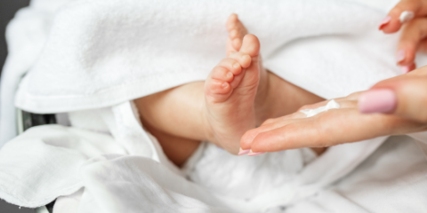 a hand applying lotion to a child foot