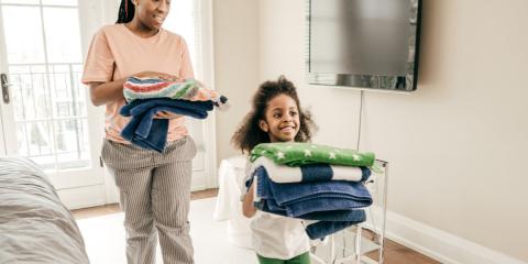 a mother and daughter carrying folded laundry