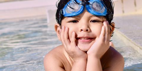 a boy with swimming googles in the shallow end of a pool