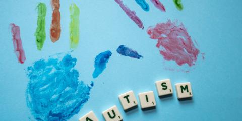 colorful hand prints with the word autism spelled out in scrabble tiles