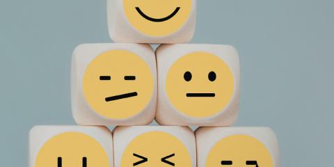 stacked dice with emoji faces of different emotions on each
