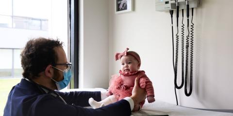 a baby sitting on an exam table with a doctor holding her
