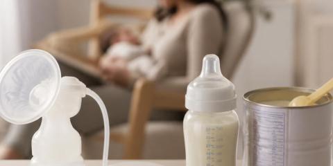 baby bottles and formula in front of a mother holding a baby